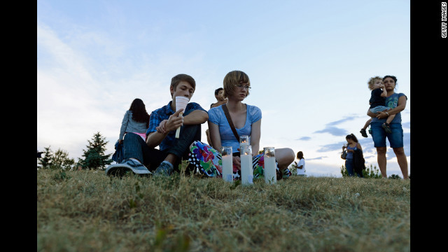 Nathan Mendoza, left, and Melissa Clark sit on the grass during a vigil.