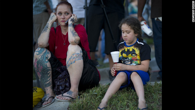 Two mourners sit on the ground at a vigil. 