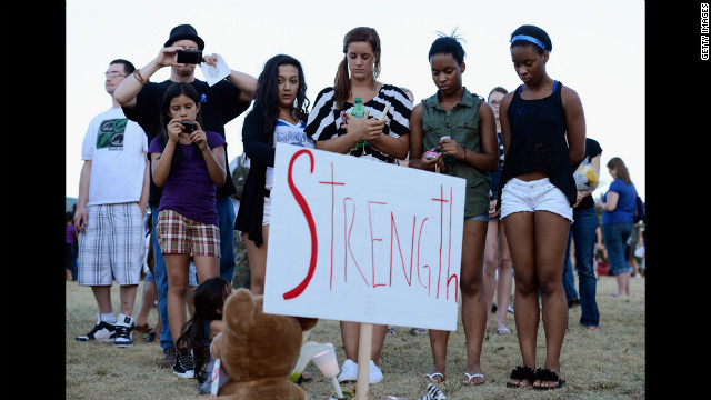 A group of teenagers stand behind a sign that reads "Strength." 