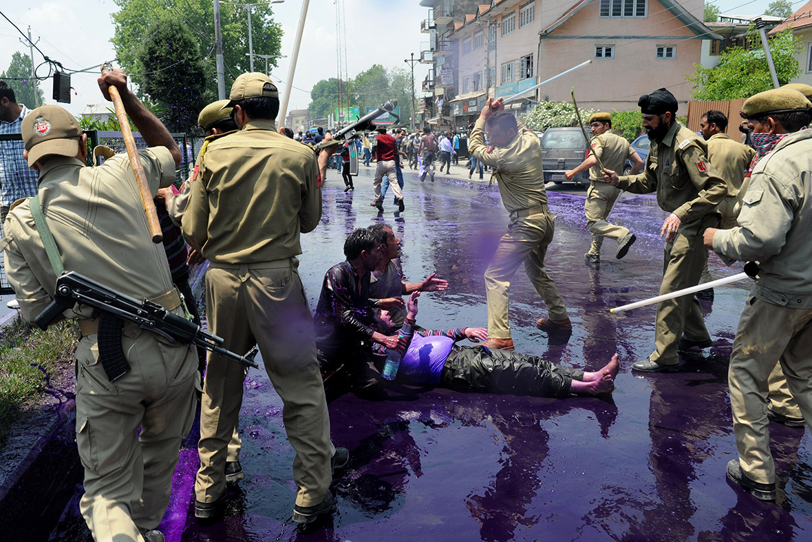 Indian police baton charge Kashmiri state government employees after spraying them with a water cannon filled with purple dye during a protest march in Srinagar