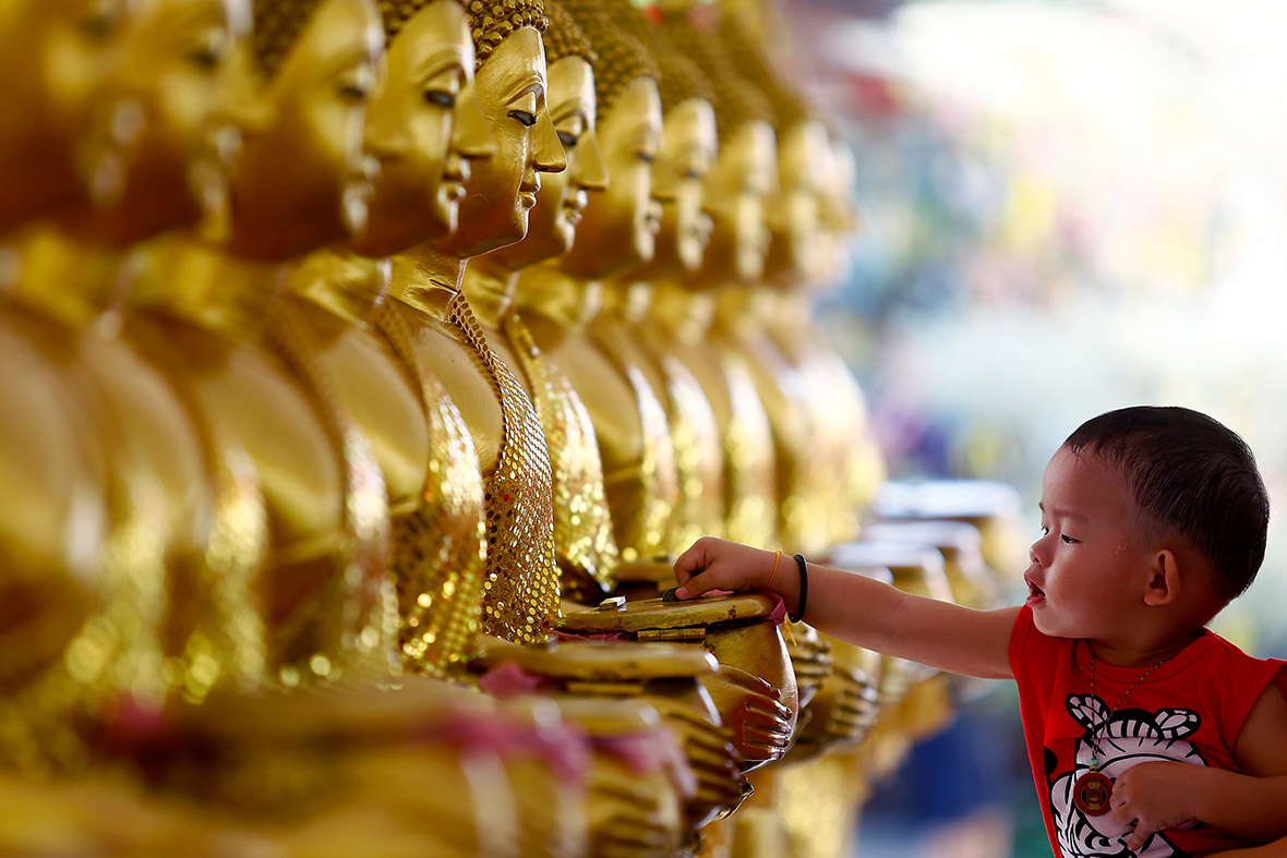 A child drops coins into golden Buddha statues on Vesak Day at the Thai Buddhist Chetawan Temple in Petaling Jaya, Malaysia. Buddhists across the world celebrate Vesak to honour the birth, enlightenment and passing of Lord Buddha 2,550 years ago