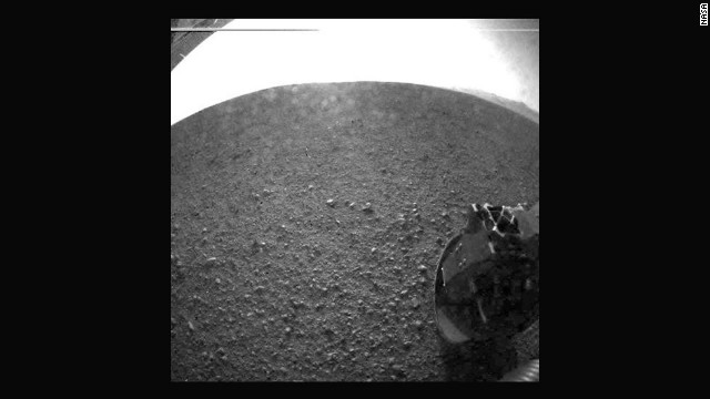 Another of the first images taken by the rover. The clear dust cover that protected the camera during landing has popped open. Part of the spring that released the dust cover can be seen at the bottom right, near the rover's wheel.