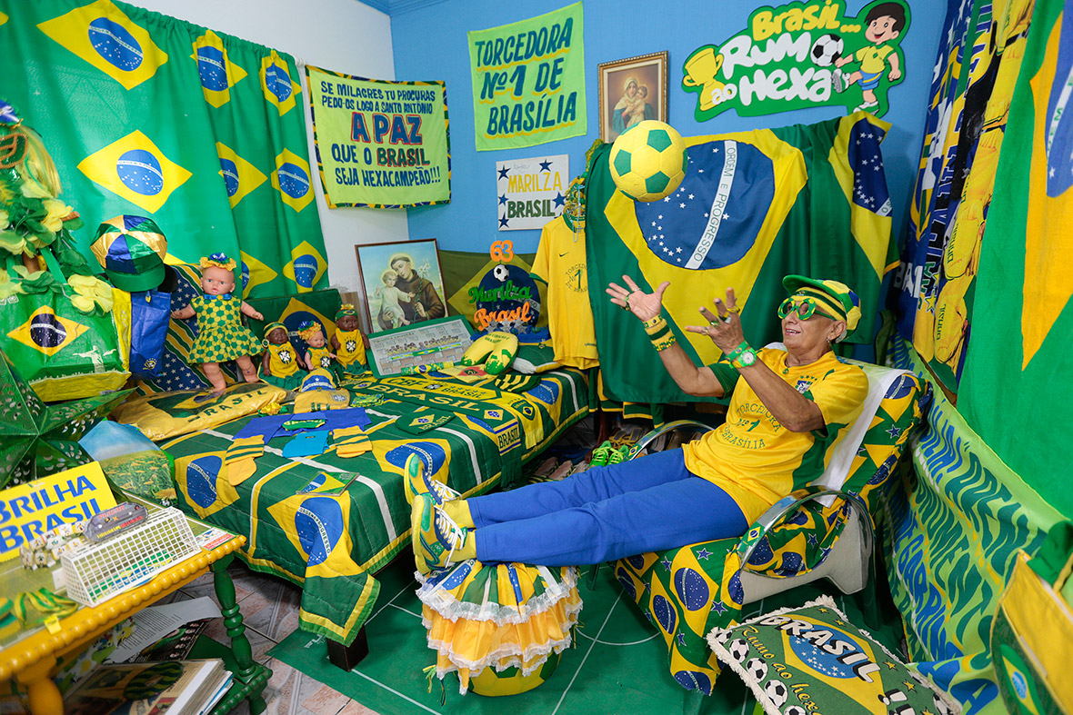 Brazilian football fan Marilza Guimaraes da Silva, 63, plays with a ball as she poses for pictures, dressed in one of her many outfits matching the colours of Brazil's national flag (green, yellow, white and blue) at her home in Brasilia
