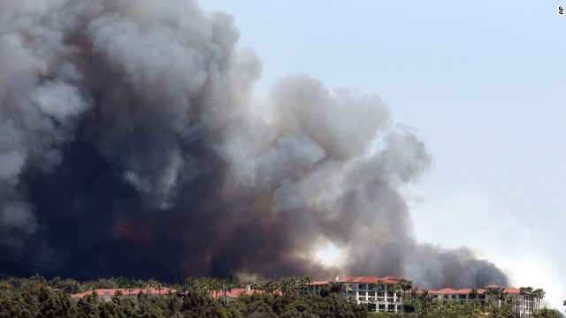 A wildfire approaches buildings in Carlsbad on May 14.