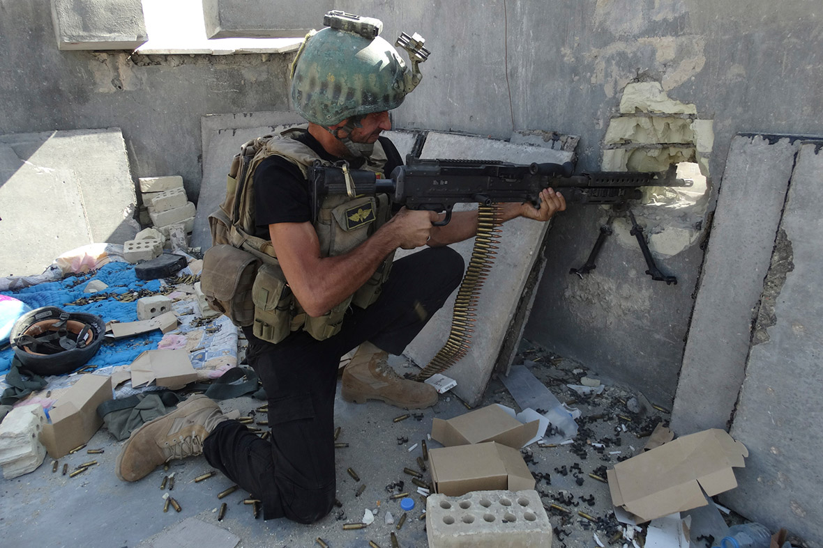 A member of the Iraqi Special Operations Forces fires through a hole in a wall during clashes with Isis militants