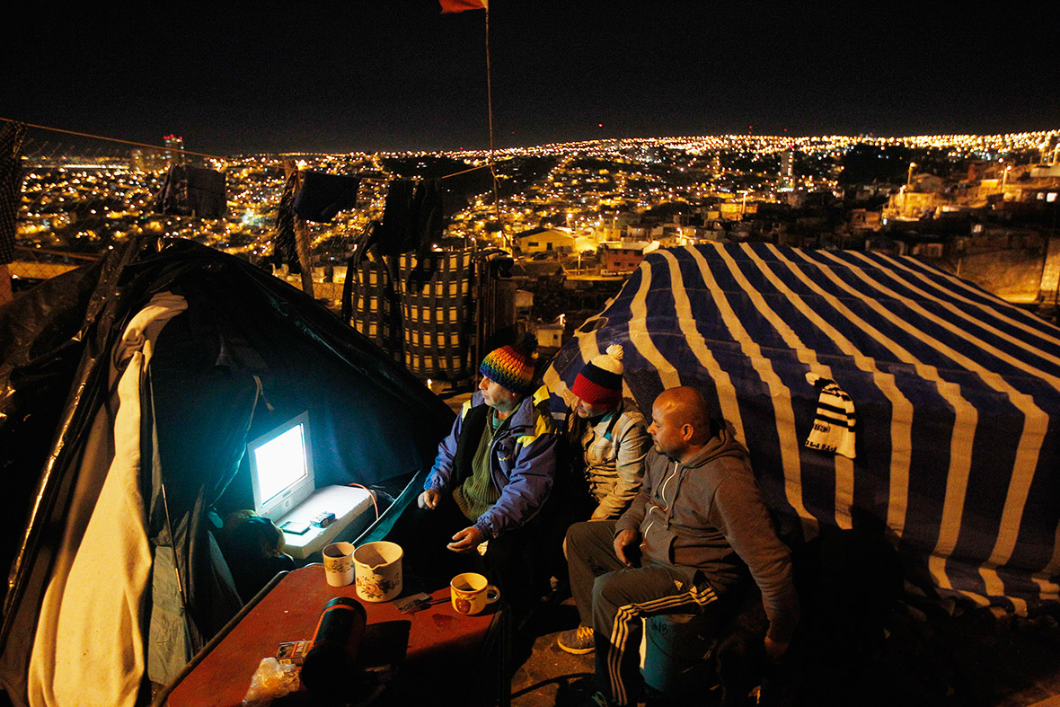Chilean football fans watch the World Cup match between Chile and Australia in their makeshift tent on the hills of Las Canas in Valparaiso city. Their homes were destroyed in a fire that burned large swathes of predominantly low-income, wooden houses, in the hills above the city in April