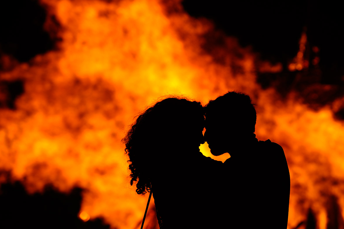 A couple embrace in front of a bonfire during a party held on the night of the San Juan on the beach of Playa de Poniente in Gijon, Spain
