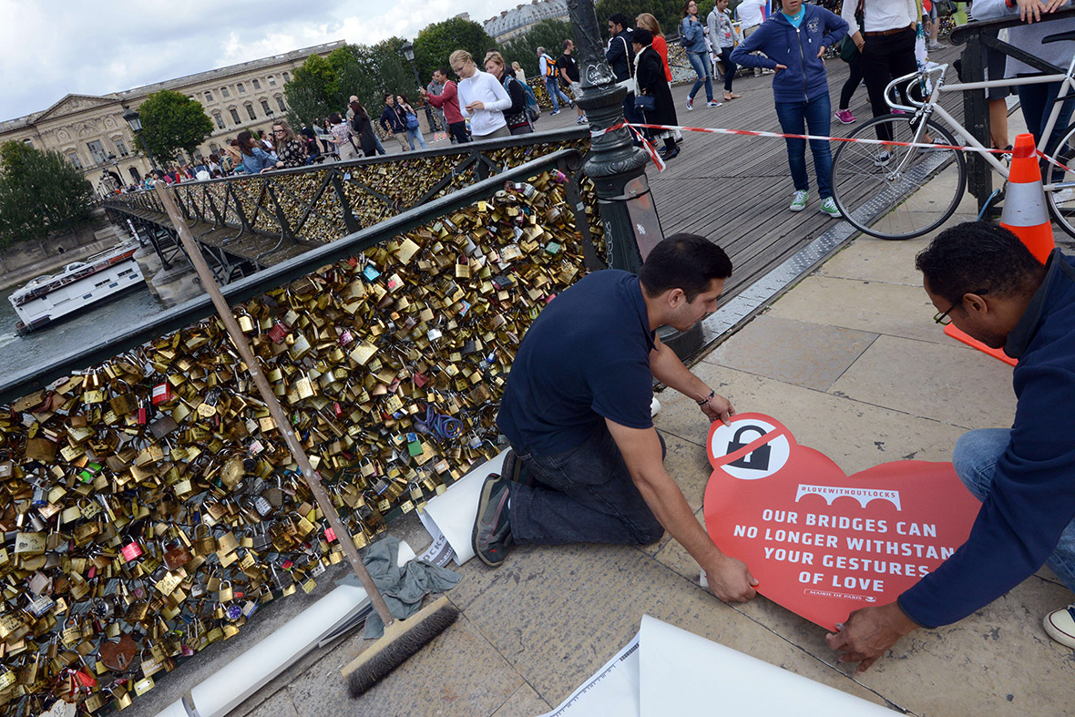 City employees position stickers urging tourists to stop clipping padlocks, or love locks, onto the railings of the Pont de l'Archeveche in Paris