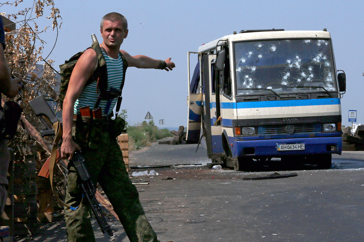 An armed pro-Russian separatist points at a bus riddled with bullet holes at a checkpoint on the outskirts of Donetsk