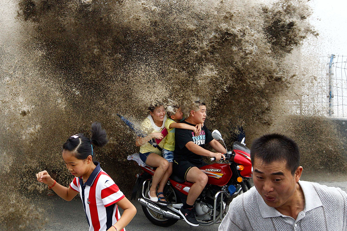 People run away as waves caused by a tidal bore surge past a barrier on the banks of Qiantang River, in Hangzhou, Zhejiang province, China...