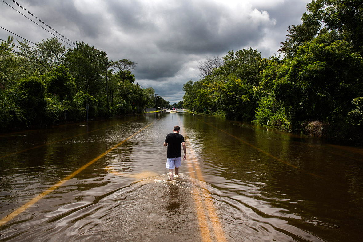 A man walks down a flooded road in Islip, New York, after more than a foot of rain hit parts of Long Island, triggering flash floods and swamping cars on major roads that were turned into rivers during the morning rush hour