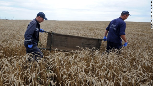 Ukrainian rescue workers walk through a wheat field with a stretcher as they collect the bodies of victims on July 19.