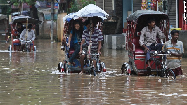 Rickshaw drivers transport commuters through floodwaters on September 5 in Gauhati, India.