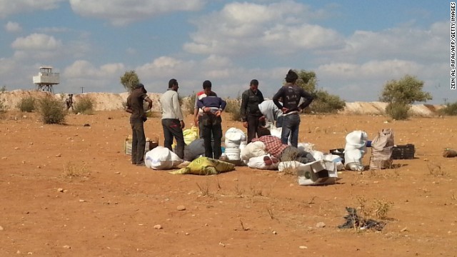 Syrians fleeing the violence stand next to their belongings as they attempt to cross into Turkey on Sunday, September 7.