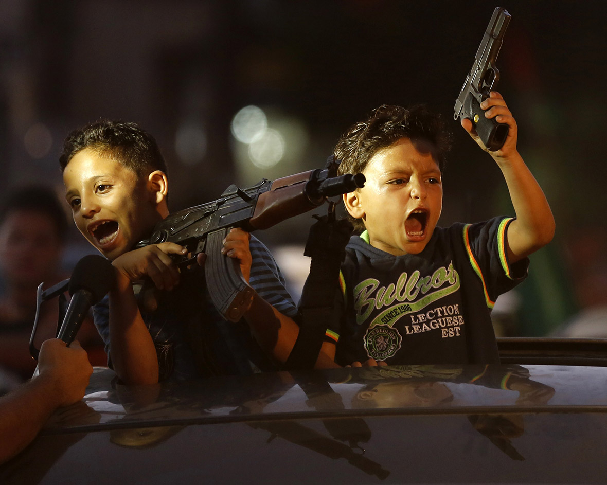 Children hold up guns as Palestinians gather in the streets of Gaza City to celebrate, after a deal was reached between Hamas and Israel to end seven weeks of fighting in the Gaza Strip