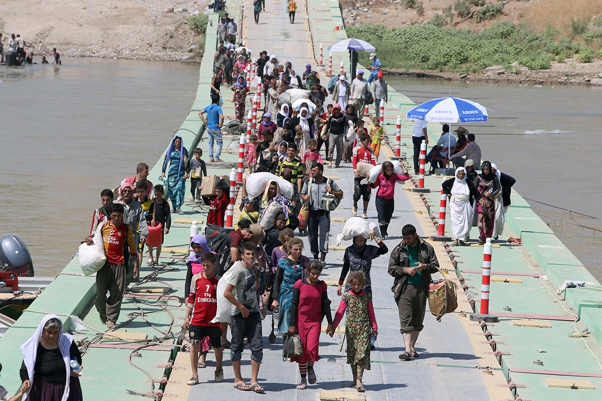 Displaced Yazidi Iraqis cross the Iraqi-Syrian border along the Fishkhabur bridge over the Tigris River.