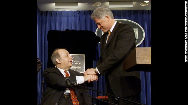 Clinton congratulates Brady in February 2000, when the White House press briefing room was named in his honor.