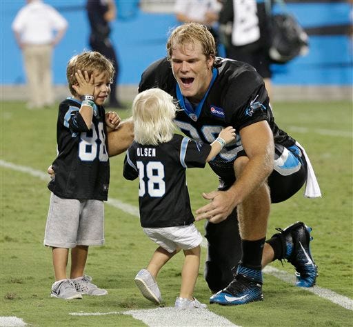 FILE - In this Aug. 7, 2015, file photo, Carolina Panthers' Greg Olsen, right, greets his children, Tate, left, and Talbot, center, during the annual Fan Fest at the NFL football team's training camp in Charlotte, N.C. When Carolina tight end Greg Olsen and Kansas City safety Eric Berry had life-changing experiences away from football, the logical next step was finding ways to help the causes that helped them. That’s the legacy of the NFL’s Walter Payton Man of the Year award _ players using their platforms to raise money for issues that are important to them. (AP Photo/Chuck Burton, File)