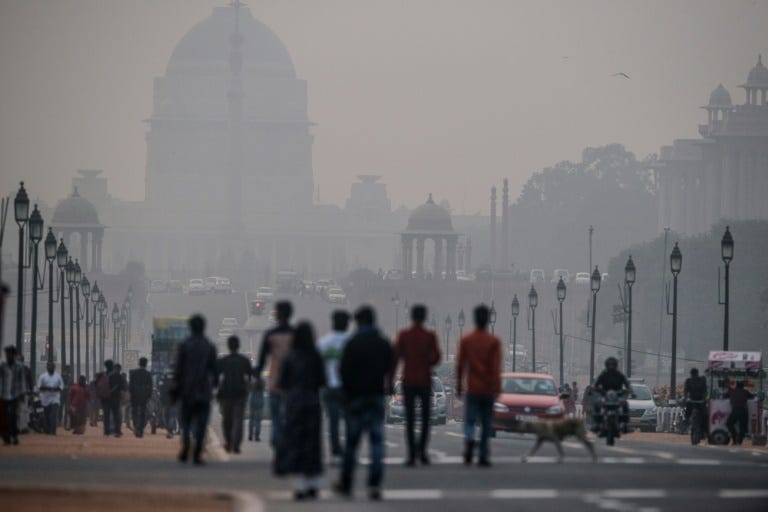 Pedestrians walk down the Rajpath in New Delhi on December 1, 2015 as smog envelopes government offices