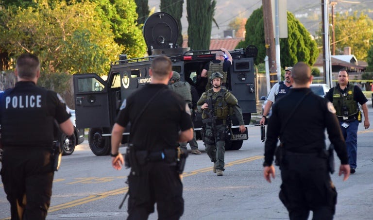 Police personnel from various departments walk along closed off streets in San Bernardino on December 2, 2015