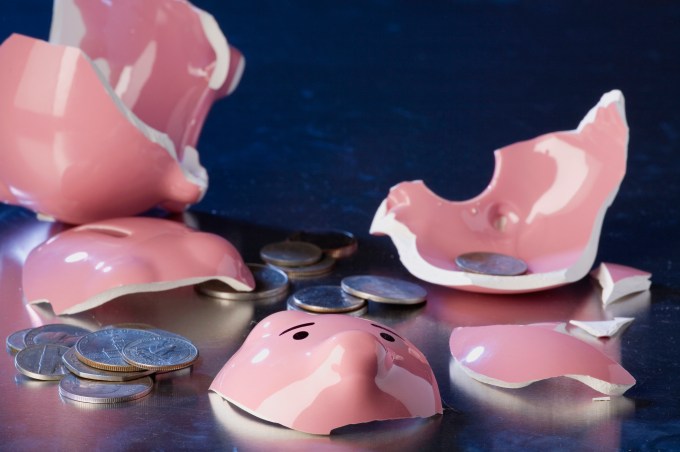 Close-up of a broken piggy bank with coins