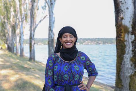 Photo of Shukri Olow standing in front of a tree-lined body of water.