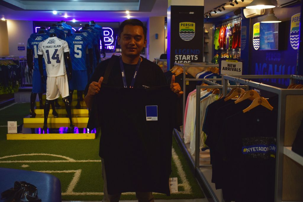 Bobotoh asal Kota Bandung, Rizal Permana (27), menunjukkan <i>T-shirt </i>atau oblong Persib Bandung yang dibelinya di Persib Merchandise Store di lantai dua Graha Persib di Kota Bandung, Jawa Barat, Sabtu (15/7/2023).