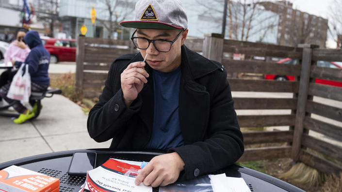 Aaron Salvador swabs his nose with a COVID-19 rapid antigen test kit outside the Watha T. Daniel-Shaw Neighborhood Library in Washington, D.C., on Wednesday December 29, 2021. <span class="copyright"> Tom Williams/CQ-Roll Call, Inc via Getty Images</span>